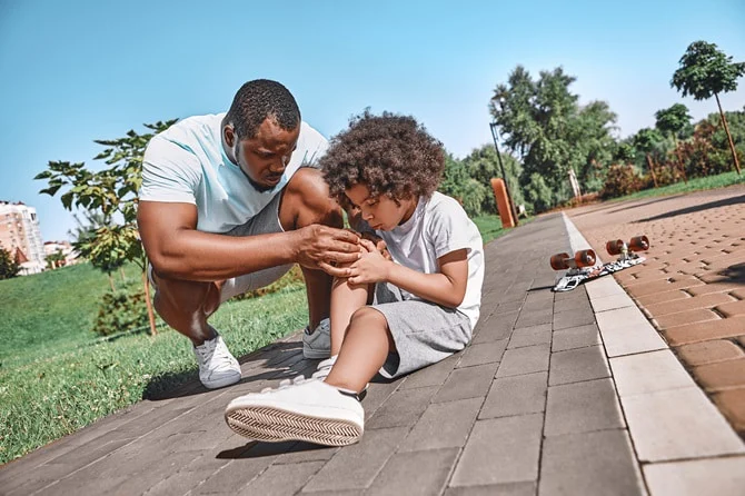 Father tending to a child who fell on a sidewalk