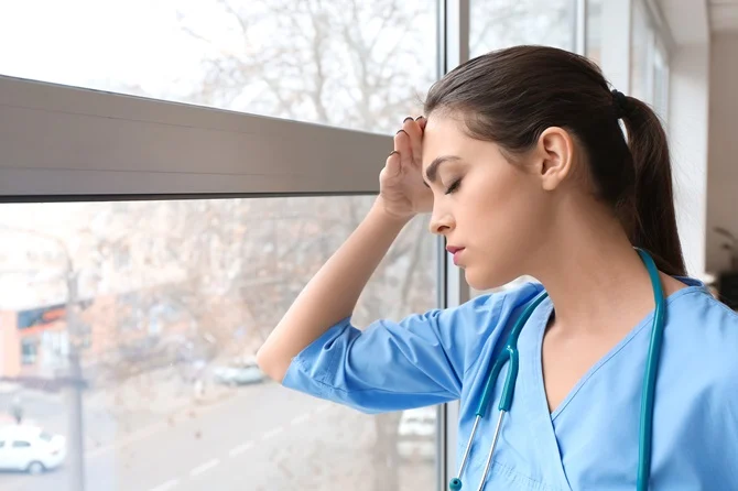 Grieving nurse leaning against a window