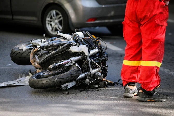 Wrecked motorcycle on the road beside a rescue worker