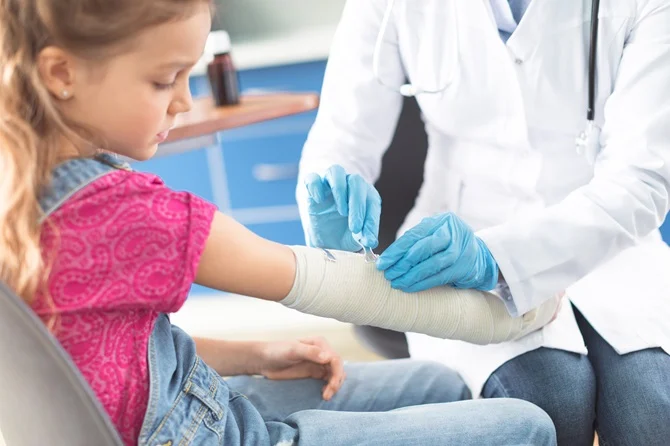 Doctor bandaging a young girl's arm