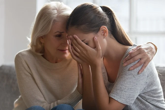 Grieving young woman comforted by an older woman