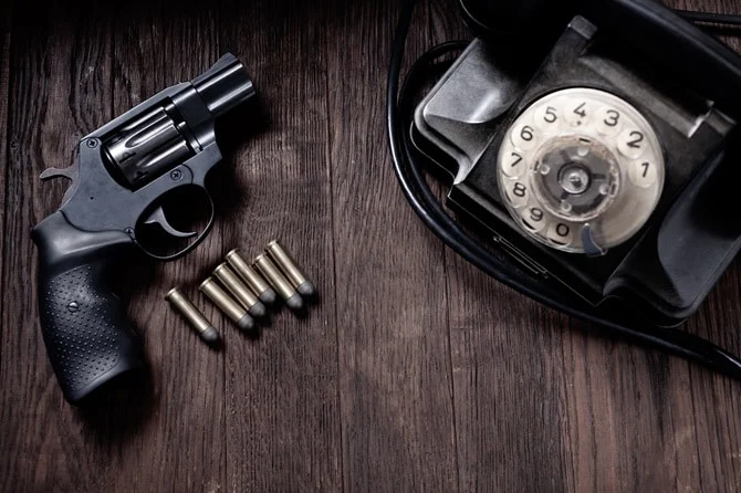 Revolver and bullets beside a rotary phone
