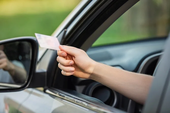 Driver handing a license out of a car window