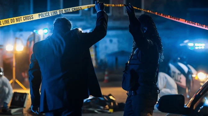 Police officers at a taped-off crime scene at night