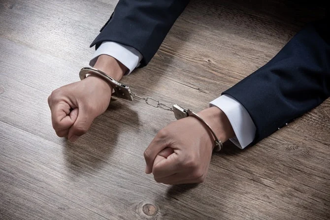 Handcuffed hands of a man in a suit
