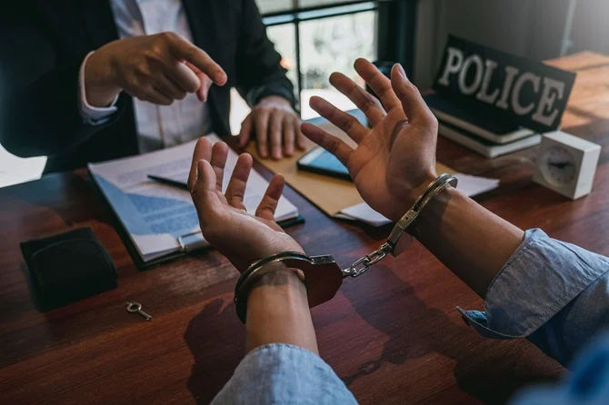 Handcuffed man at a police desk