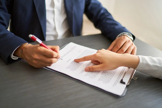 Attorney pointing out a document for a client to sign