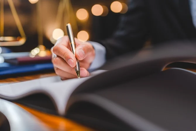 Attorney writing in a notebook beside scales of justice