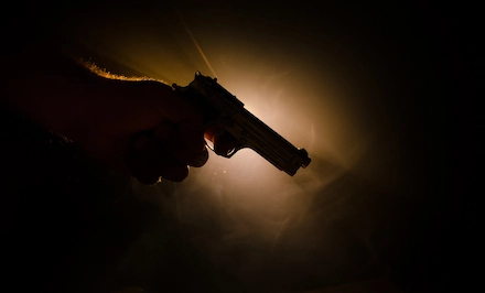 Hand holding a handgun in the dark
