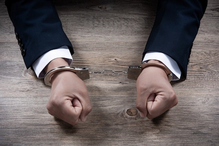 Handcuffed hands of a man in a suit