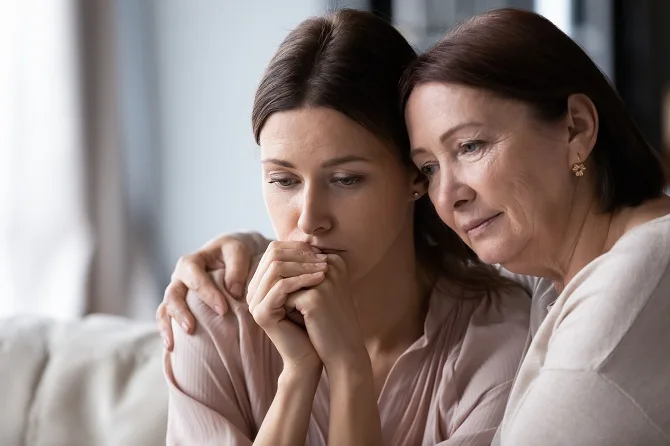 Grieving woman comforted by an older woman