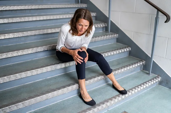 Woman holding her knee after a fall on stairs