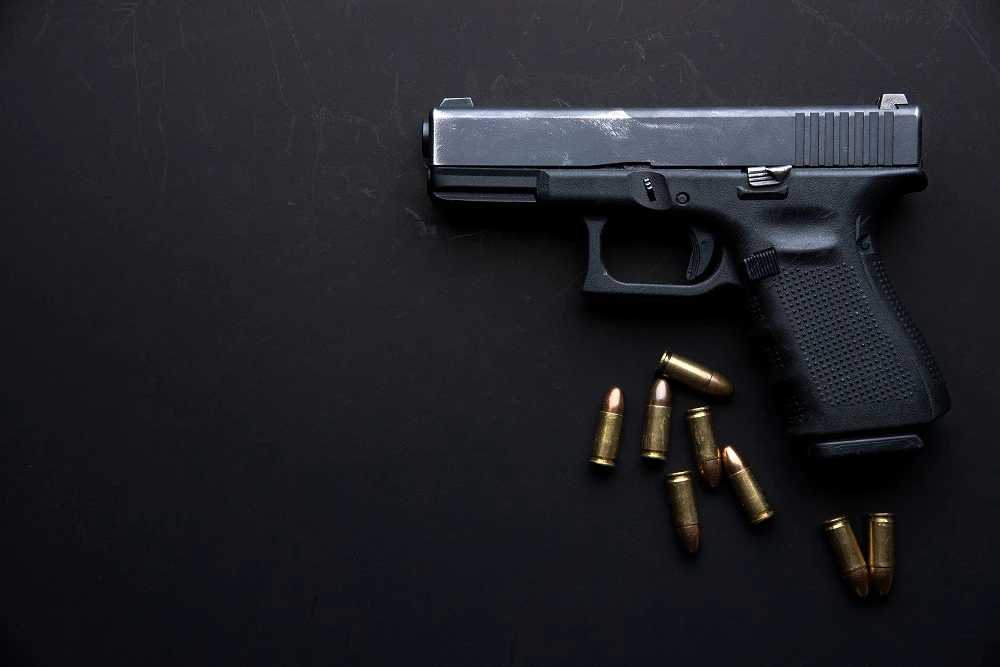 Handgun and bullets on a dark surface