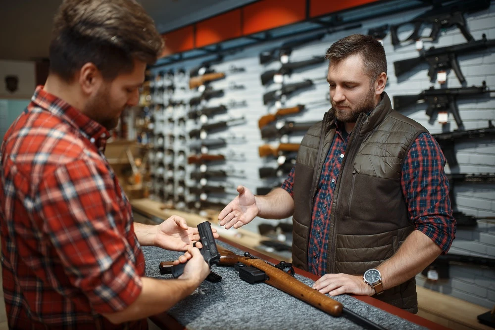 Customer examining a handgun at a gun store counter